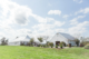 Outdoor wedding venue with a white tent and barn under a blue sky.