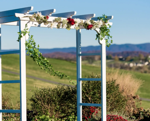 Wedding arbor adorned with greenery and flowers, set against a picturesque landscape at On Sunny Slope Farm, ideal for romantic celebrations and ceremonies.